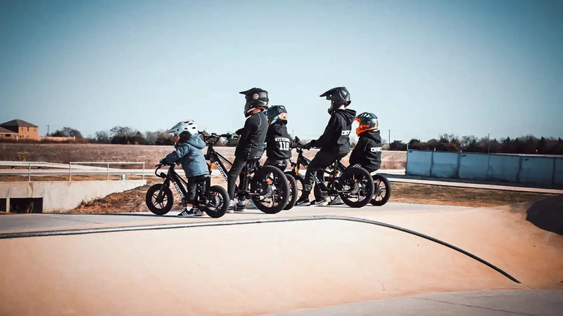 Children on small bikes with helmets lined up on a track