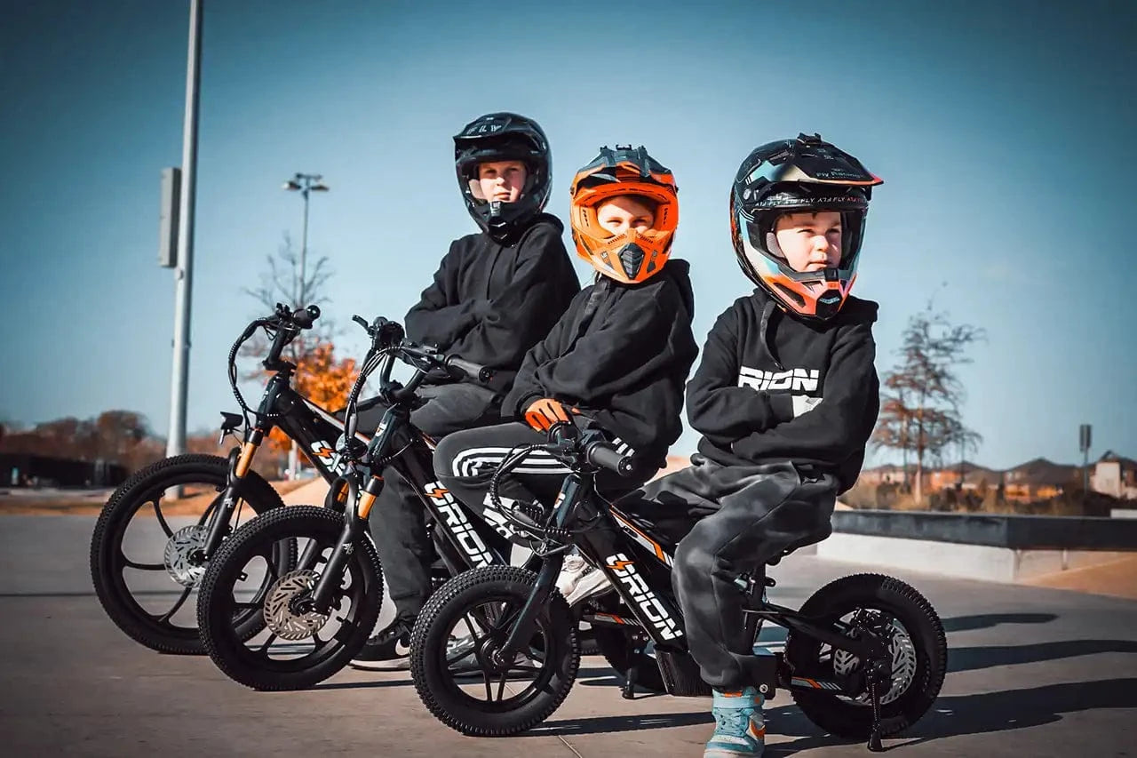 Three children on balance bikes with helmets in a park setting